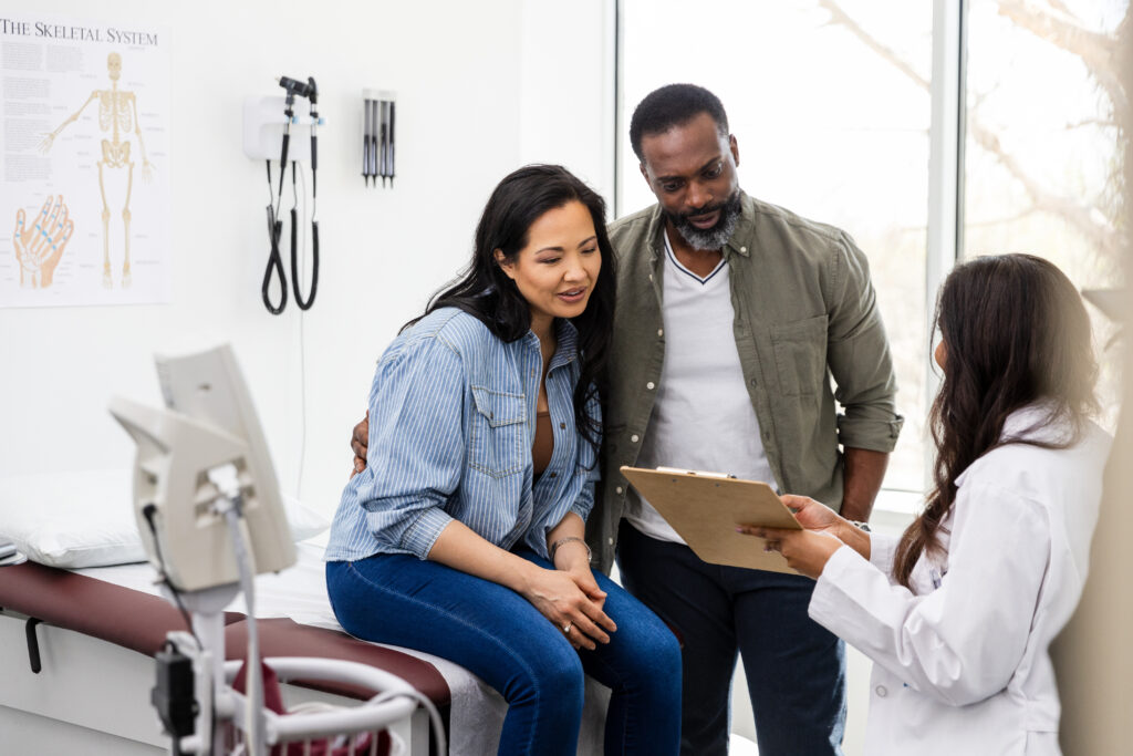 Unrecognizable female doctor talks with the couple in her office